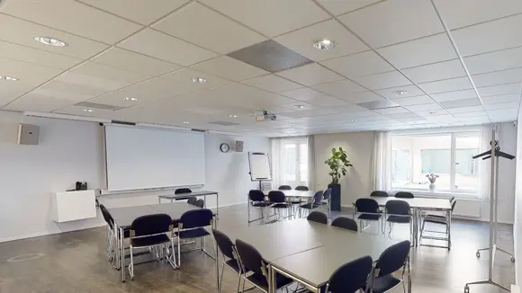 Et lyst mødelokale med en bordopsætning