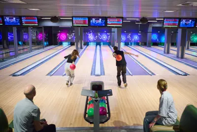 A group at the bowling alley while two people are bowling