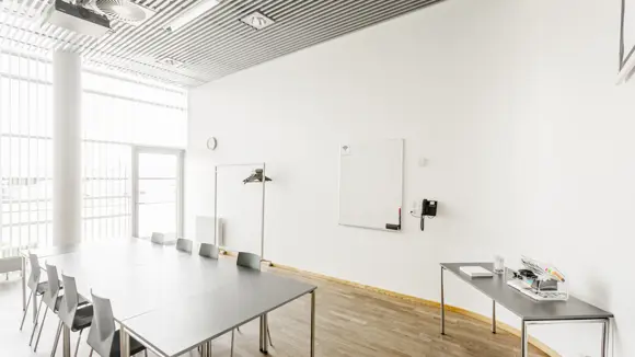 Et lyst mødelokale med en bordopsætning