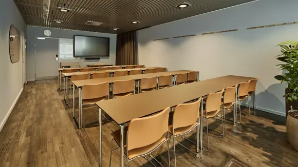 Et lyst mødelokale med en bordopsætning