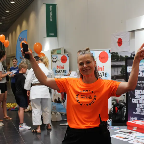 Employee standing in the foyer with arms raised above their head