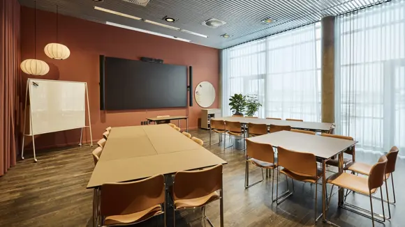 Et lyst mødelokale med en bordopsætning