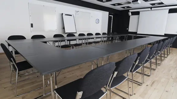 Et lyst mødelokale med en bordopsætning