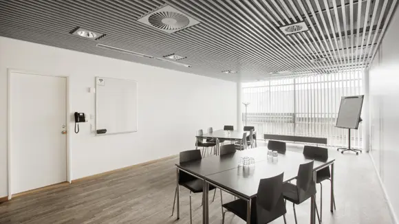 Et lyst mødelokale med en bordopsætning