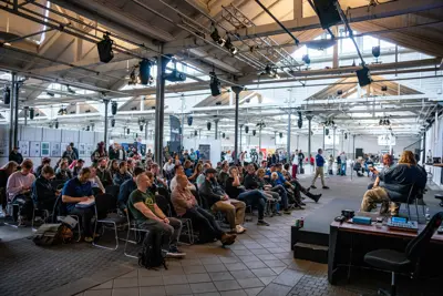 En konference i Øksnehallen med et siddende publikum og en taler