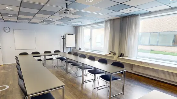 Et lyst mødelokale med en bordopsætning