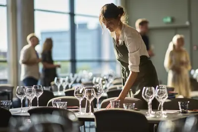 En tjener der er ved at dække op til frokost
