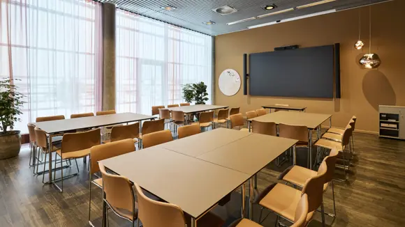 Et lyst mødelokale med en bordopsætning