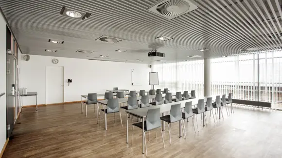 Et lyst mødelokale med en bordopsætning