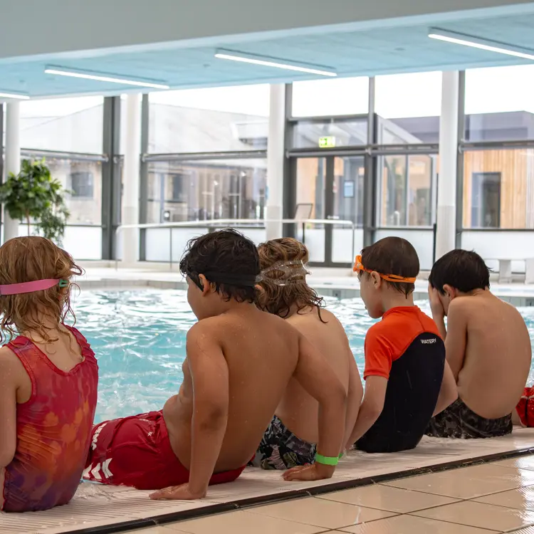 Instruktør sidder på bassinkanten til en camp