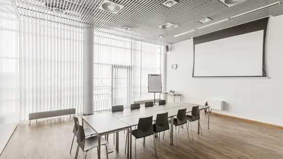 Et lyst mødelokale med en bordopsætning