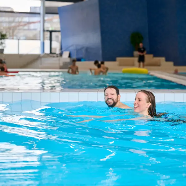 To glade hotelgæster der svømmer i Vandkulturhuset