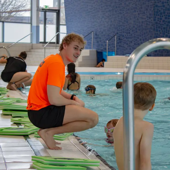 Instruktør sidder på bassinkanten