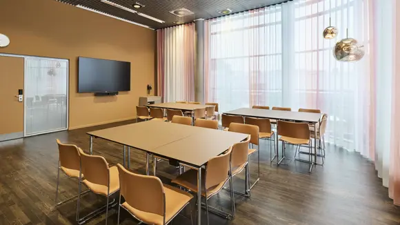 Et lyst mødelokale med en bordopsætning