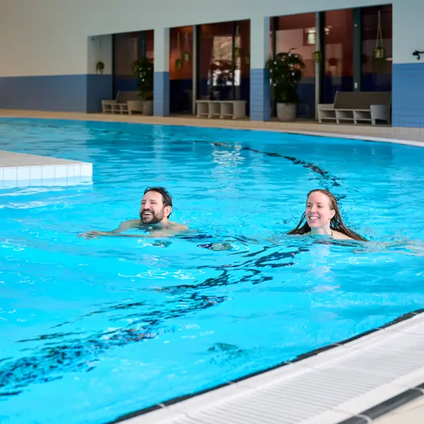 mand og dame svømmer i bassin smilende